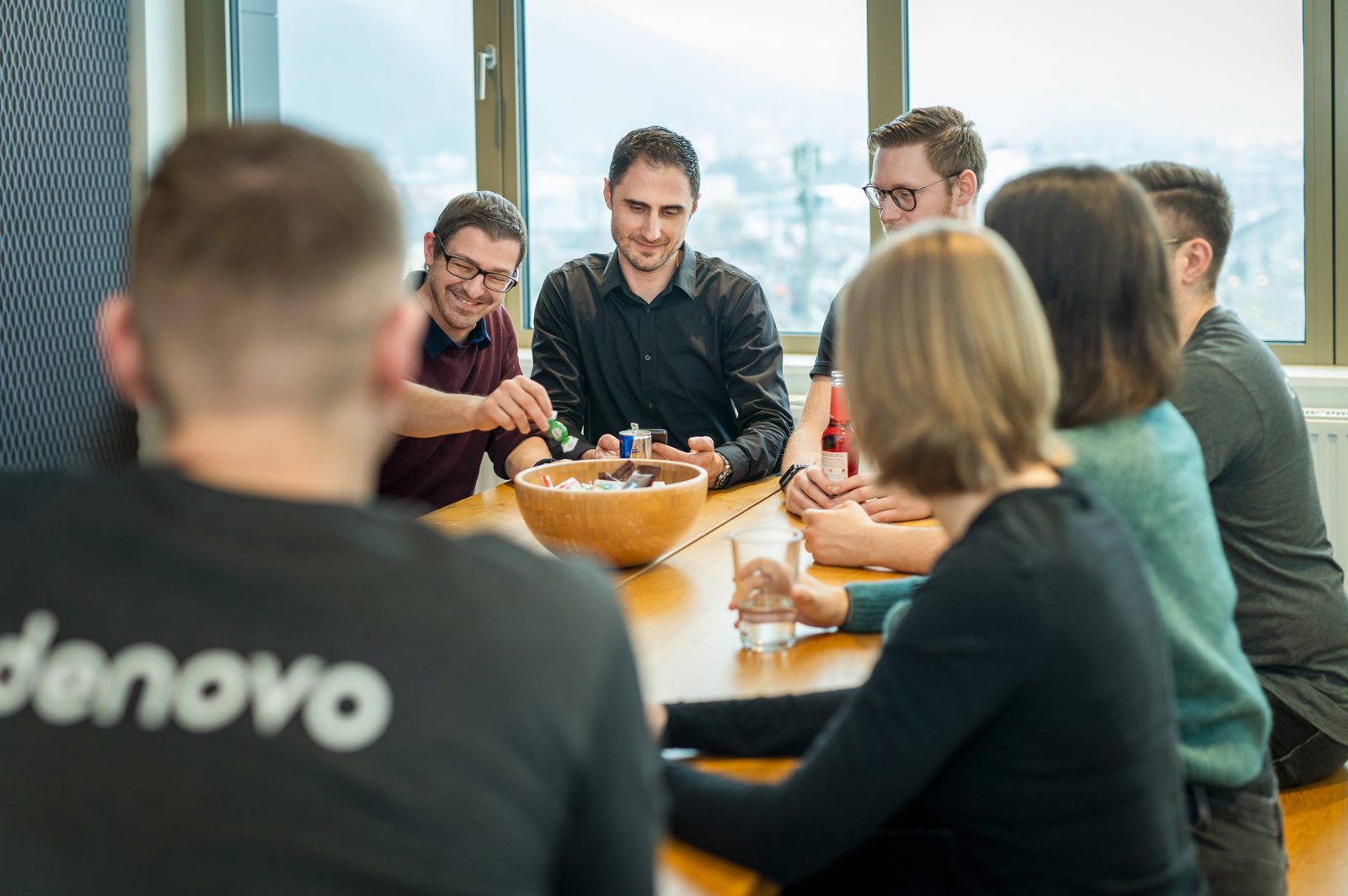 Team sitzt gemeinsam an einem Tisch im Denovo-Büro