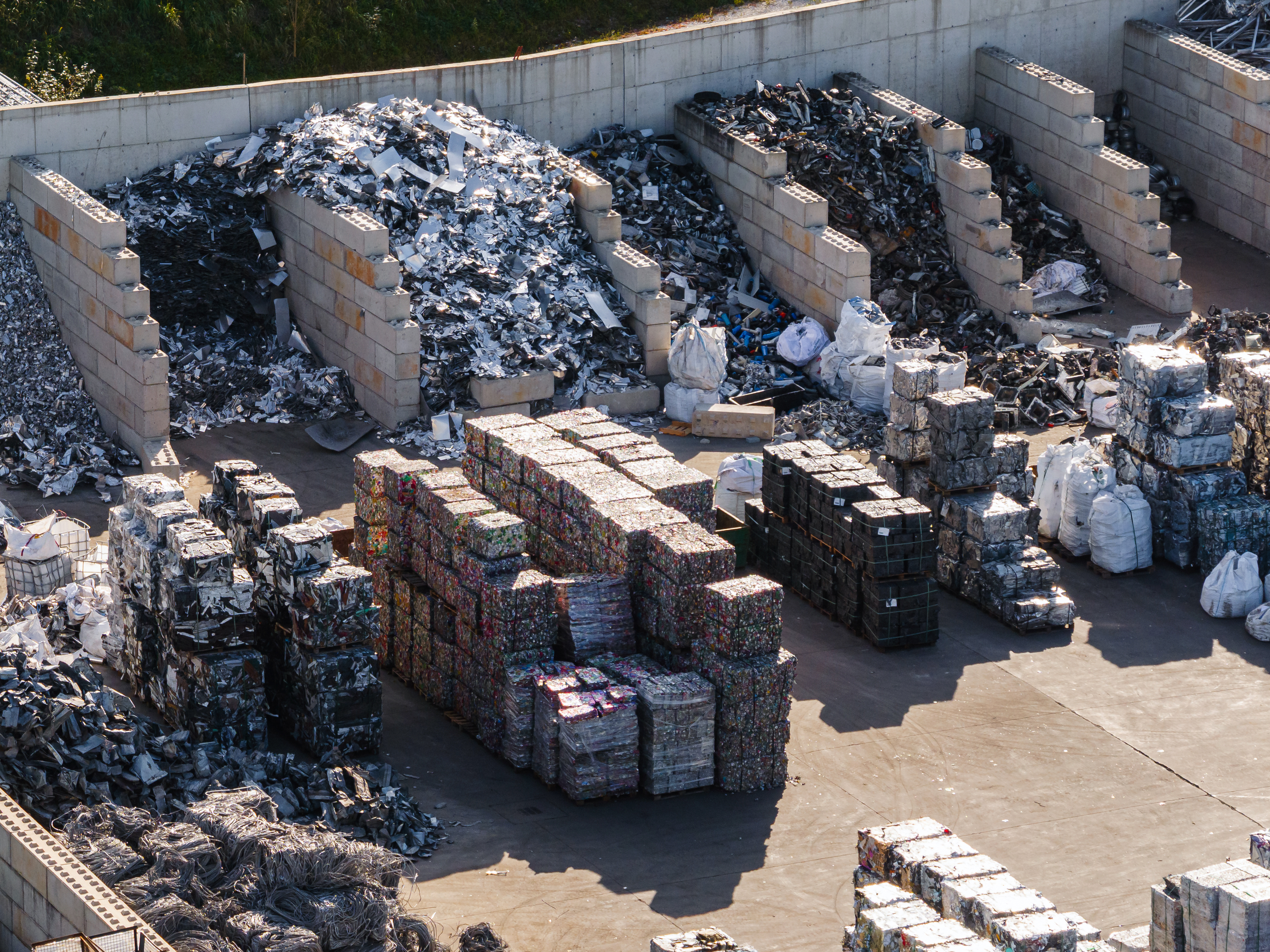 Sortierte Metallschrotte und gepresste Wertstoffballen auf einem Recyclinggelände