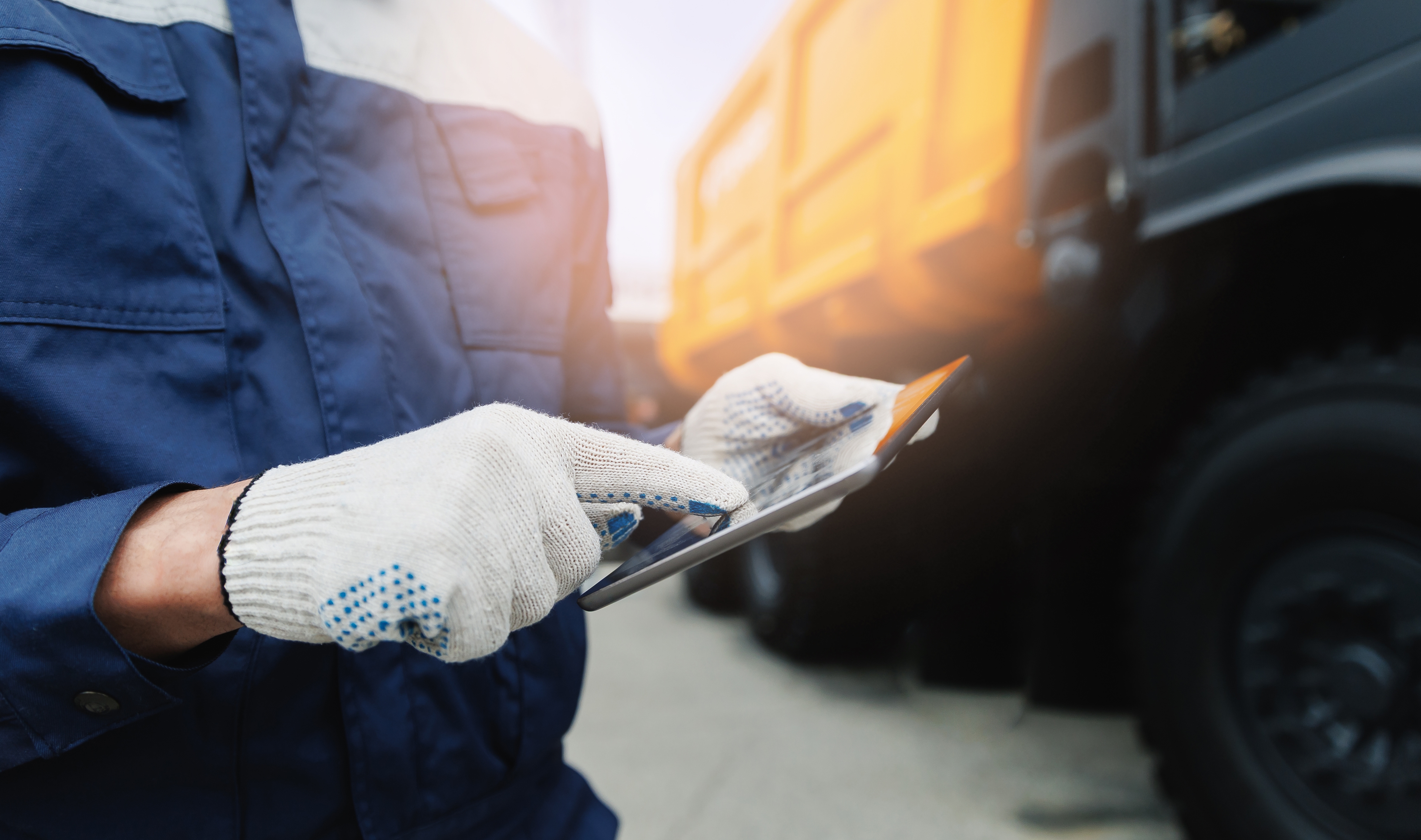 Person nutzt ein Tablet neben einem Entsorgungsfahrzeug